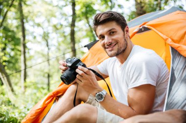 Oturma ve turistik çadırda fotoğraf makinesi kullanarak adam turizm