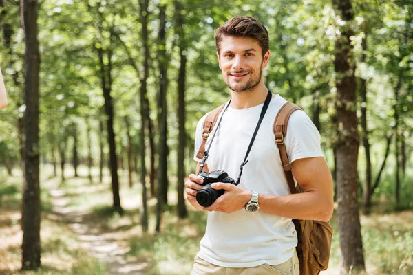 Feliz joven fotógrafo sosteniendo la cámara de fotos moderna al aire libre —  Fotos de Stock