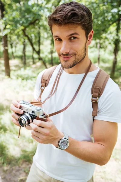 Man with backpack taking photos using old camera in forest — Stock Photo, Image