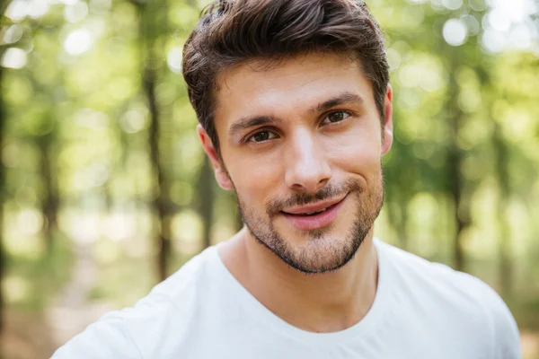 Glücklich schöner junger Mann trägt weißes T-Shirt im Wald — Stockfoto