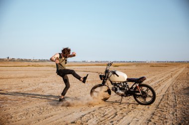Adam motorsikletiyle yakınındaki toz ayakta yapma