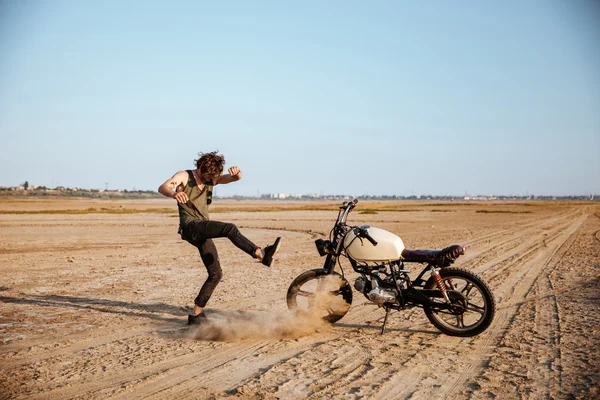 Muž, takže prach stojící poblíž jeho motocyklu — Stock fotografie