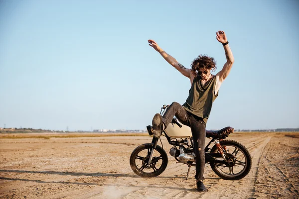 Hombre haciendo polvo de pie cerca de su motocicleta — Foto de Stock