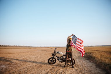 Çölde Amerikan bayrağı tutarak altın kask içinde adam
