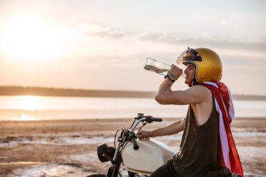 Onun motosiklet üzerinde otururken içme adam