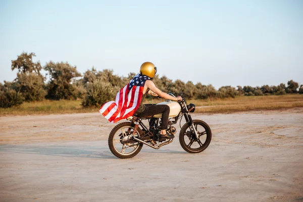 美国国旗披着斗篷，驾驶摩托车的男子的侧视图 — 图库照片