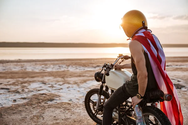 Hombre de oro en capa americana sentado en su motocicleta —  Fotos de Stock