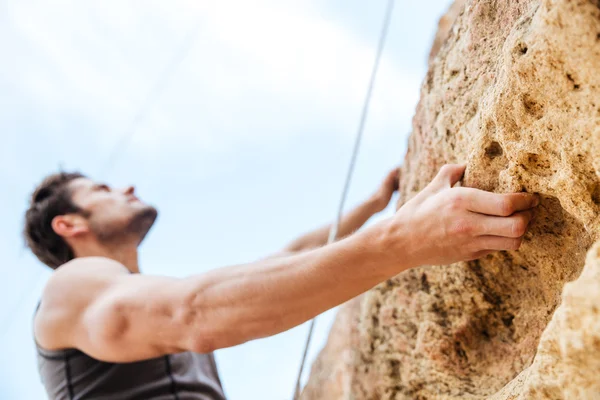 Joven deportista subiendo por un acantilado de roca —  Fotos de Stock