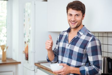 Mutfak üzerinde duran ve başparmak gösterilmesini neşeli genç adam