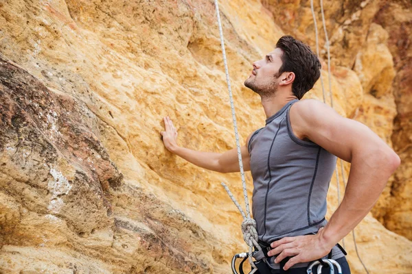 Young handsome sportsman getting ready to climb a cliff — Stock Photo, Image