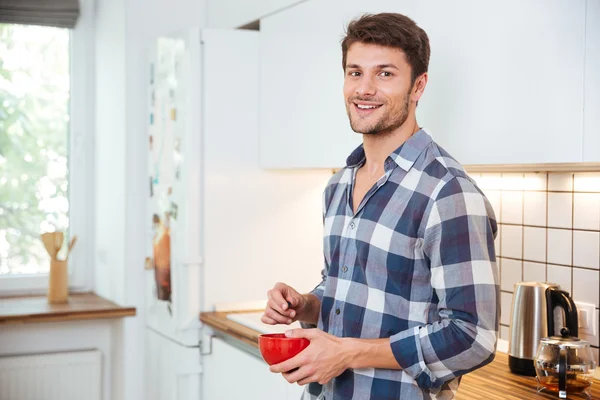 Jovem sorridente em pé na cozinha — Fotografia de Stock