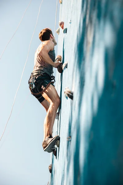 Młody człowiek wykonuje ćwiczenia w wspinaczka górska na ścianie praktyki — Zdjęcie stockowe