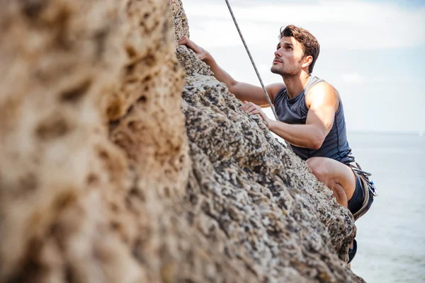 Junger Mann klettert natürliche Felswand — Stockfoto