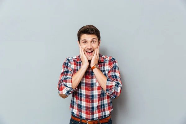Sorprendido hombre excitado en camisa a cuadros de pie con la boca abierta — Foto de Stock