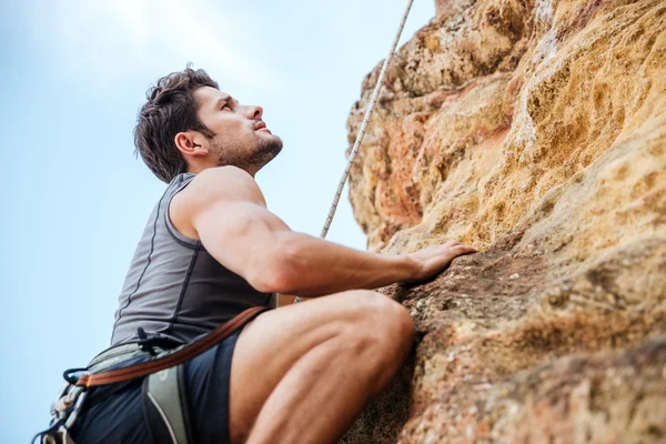 Junger Mann klettert in Berg eine steile Wand hoch — Stockfoto