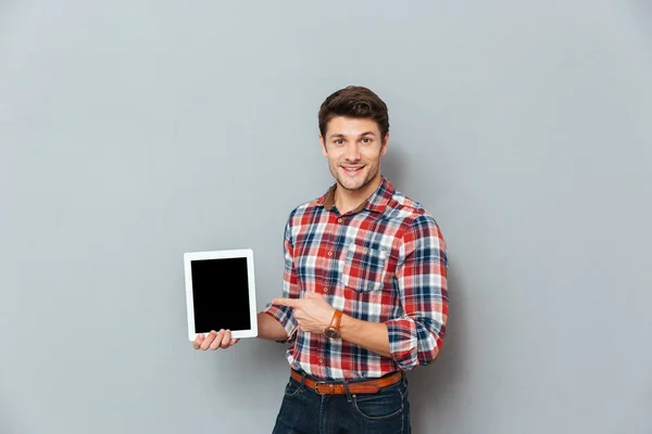 Vrolijke man in geruite hemd wijzen op leeg scherm tablet — Stockfoto