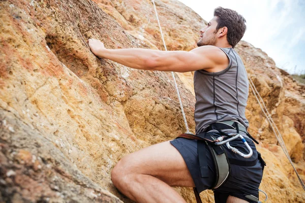 Junger Mann klettert in Berg eine steile Wand hoch — Stockfoto