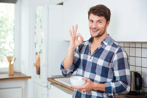 Jovem feliz mostrando ok sinal na cozinha — Fotografia de Stock