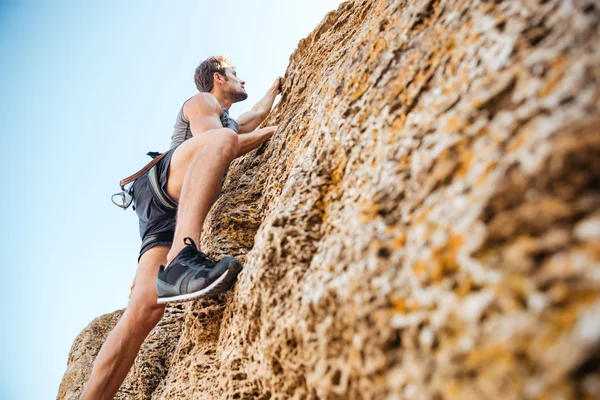 Joven deportista subiendo por un acantilado de roca —  Fotos de Stock