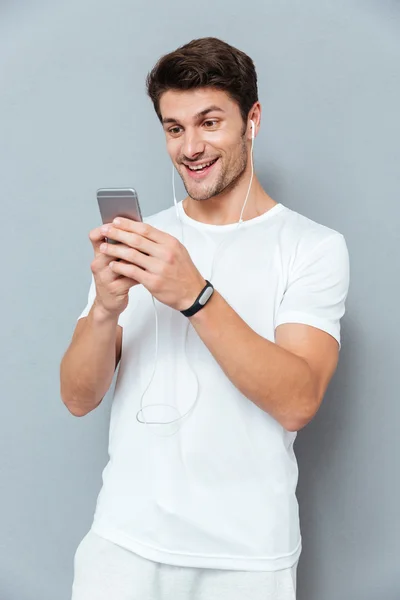 Szczęśliwy atrakcyjny młody człowiek słuchania muzyki ze smartfona — Zdjęcie stockowe
