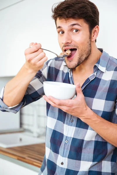 Man äter frukost och äta flingor med mjölk på kök — Stockfoto