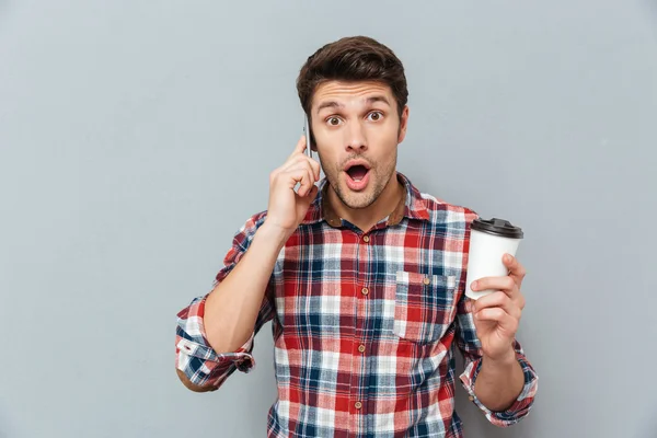 Hombre sorprendido sosteniendo el café para llevar y hablando por teléfono móvil — Foto de Stock