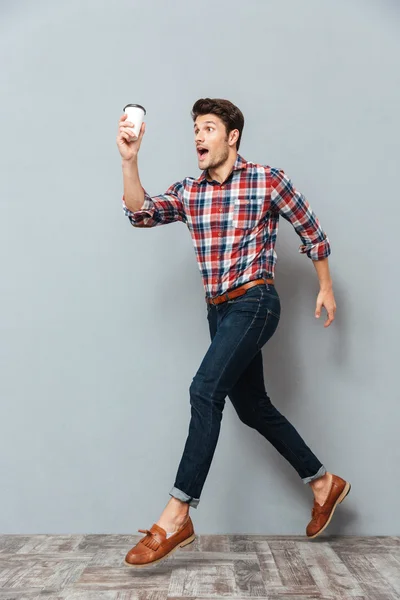 Attraktiver junger Mann mit einer Tasse Kaffee zum Mitnehmen und Laufen — Stockfoto