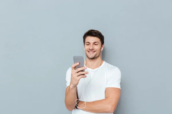 Boldog vonzó fiatal férfi hallgató-hoz zene-ból smartphone — Stock Fotó
