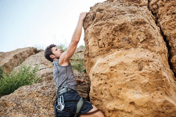 Man reaching for a grip while he rock climbs — Stock Photo, Image