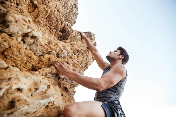Hombre buscando un agarre mientras él sube a la roca —  Fotos de Stock