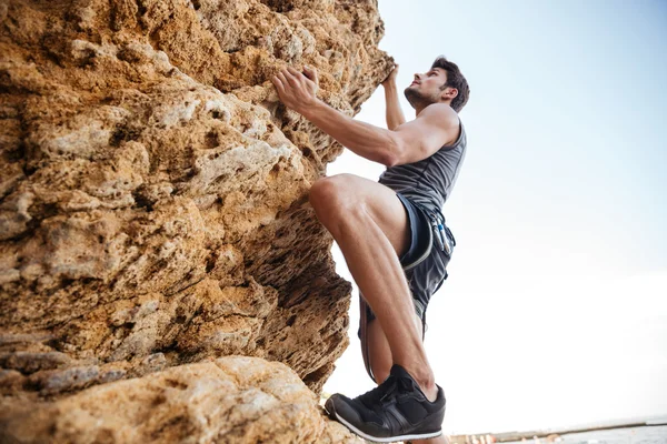 Hombre joven escalando la pared rocosa natural —  Fotos de Stock