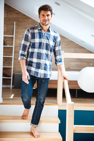 Atractivo joven caminando descalzo en las escaleras en casa — Foto de Stock