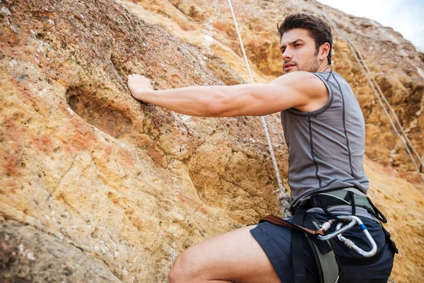 Young man climbing a steep wall in mountain — Stock Photo, Image