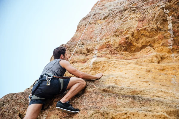 Junger Sportler klettert eine Felswand hinauf — Stockfoto