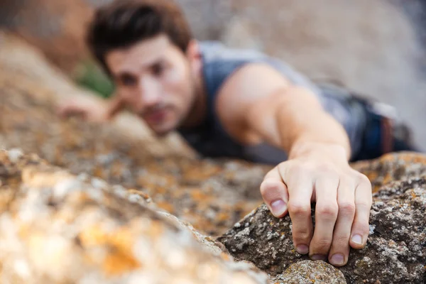 Hombre buscando un agarre mientras él sube a la roca —  Fotos de Stock