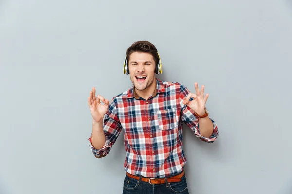 Hombre en los auriculares que muestran signo ok y escuchar música — Foto de Stock