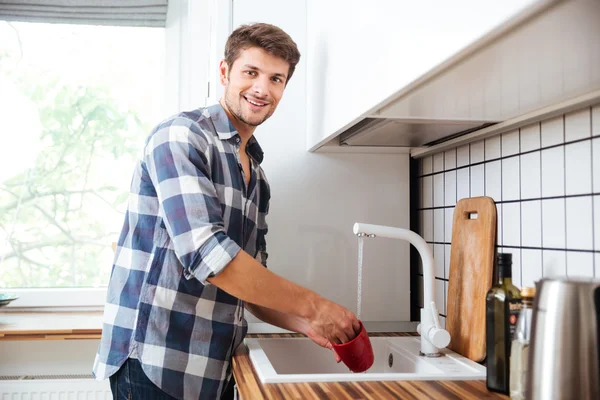幸せな若い男、台所に立っていると洗濯料理 — ストック写真
