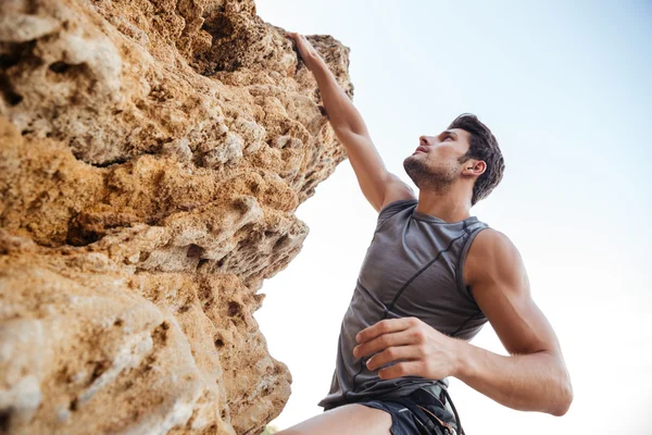 Man reaching for a grip while he rock climbs Royalty Free Stock Images