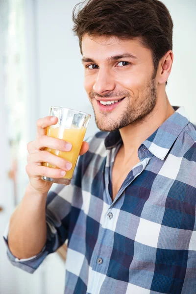 Happy young man in plaid shirt drinking juice at home — Stock Photo, Image