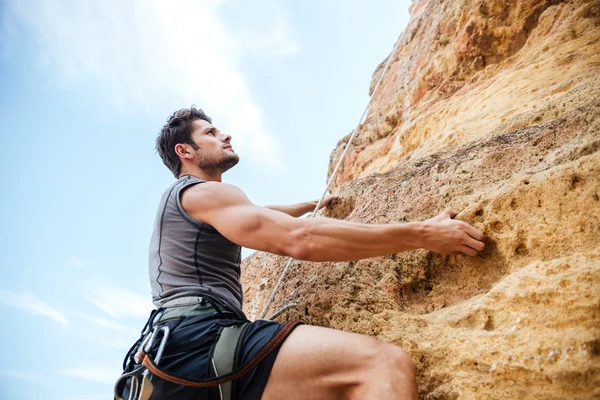 Joven deportista subiendo por un acantilado de roca —  Fotos de Stock