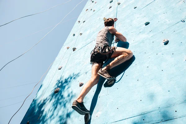 Joven haciendo ejercicio en escalada en la pared de práctica — Foto de Stock