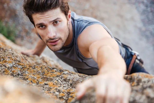 Mann greift nach Griff, während er klettert — Stockfoto