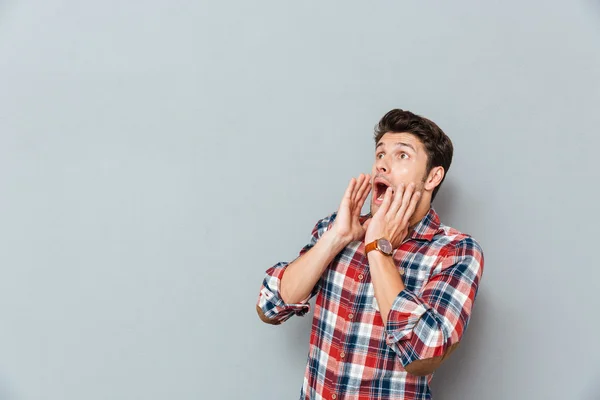 Asustado sorprendido hombre en camisa a cuadros mirando hacia otro lado y gritando — Foto de Stock