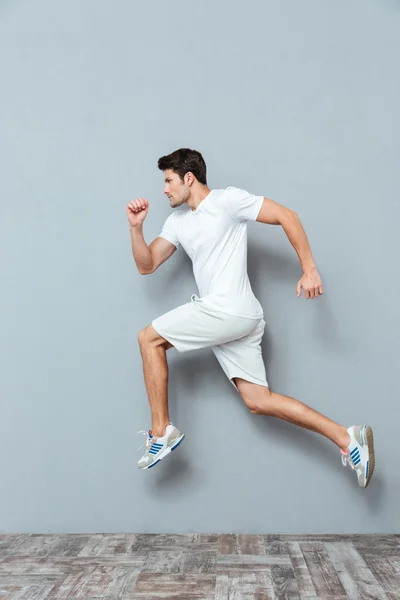 Joven hombre atlético serio saltando aislado — Foto de Stock