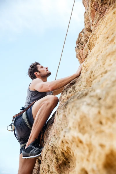 Joven deportista subiendo por un acantilado de roca —  Fotos de Stock