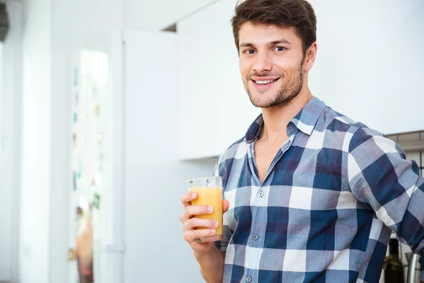 Jovem alegre com copo de suco fresco na cozinha — Fotografia de Stock