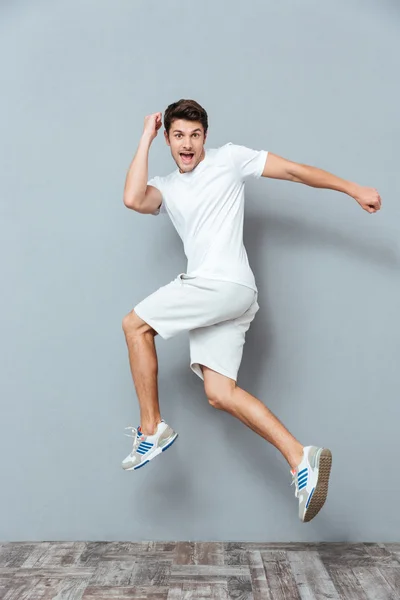 Смішний чоловік стрибає на сірому фоні — стокове фото