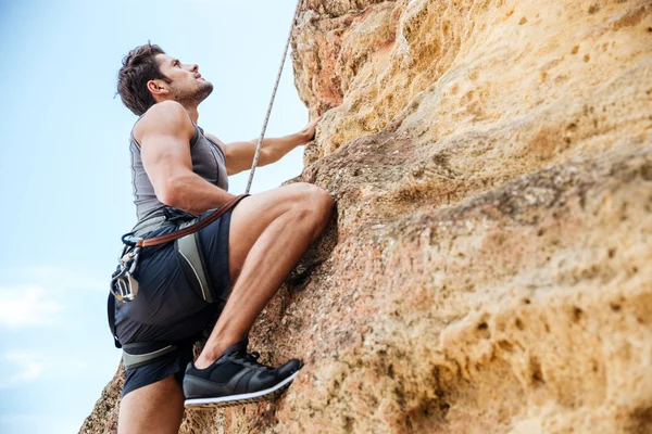 Young man climbing a steep wall in mountain Royalty Free Stock Photos