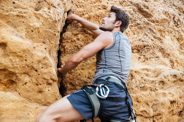 Young sportsman climbing up a rock cliff Stock Photo