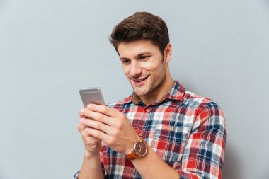 Mutlu genç adam ekose gömlek cep telefonu kullanarak